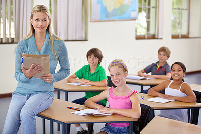 Buy stock photo Portrait, teacher and woman with students in classroom, smile and holding folder. Happiness, female educator and group of children ready for learning, education or teaching in elementary school class