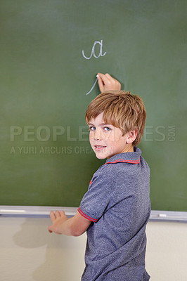 Buy stock photo Portrait, chalk and boy drawing on a board for child development, confidence and art for learning. Academic, creative and kid student writing on a blackboard in the classroom with face and happy