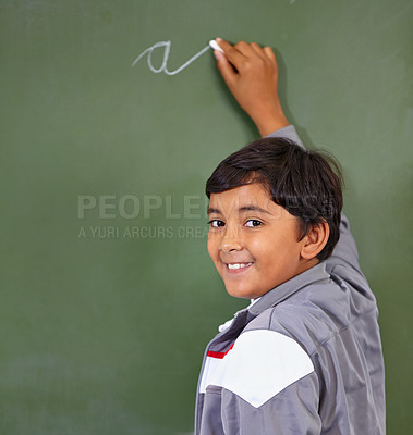 Buy stock photo Portrait, chalk and boy writing on a board for child development, confidence and art for learning. Academic, creative and kid student drawing on a blackboard in the classroom with face and excited