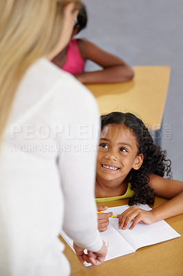 Buy stock photo Teacher woman, classroom and help girl at desk with notebook, advice and knowledge for education. People, learning and development with person, child and check book for progress, school or academy