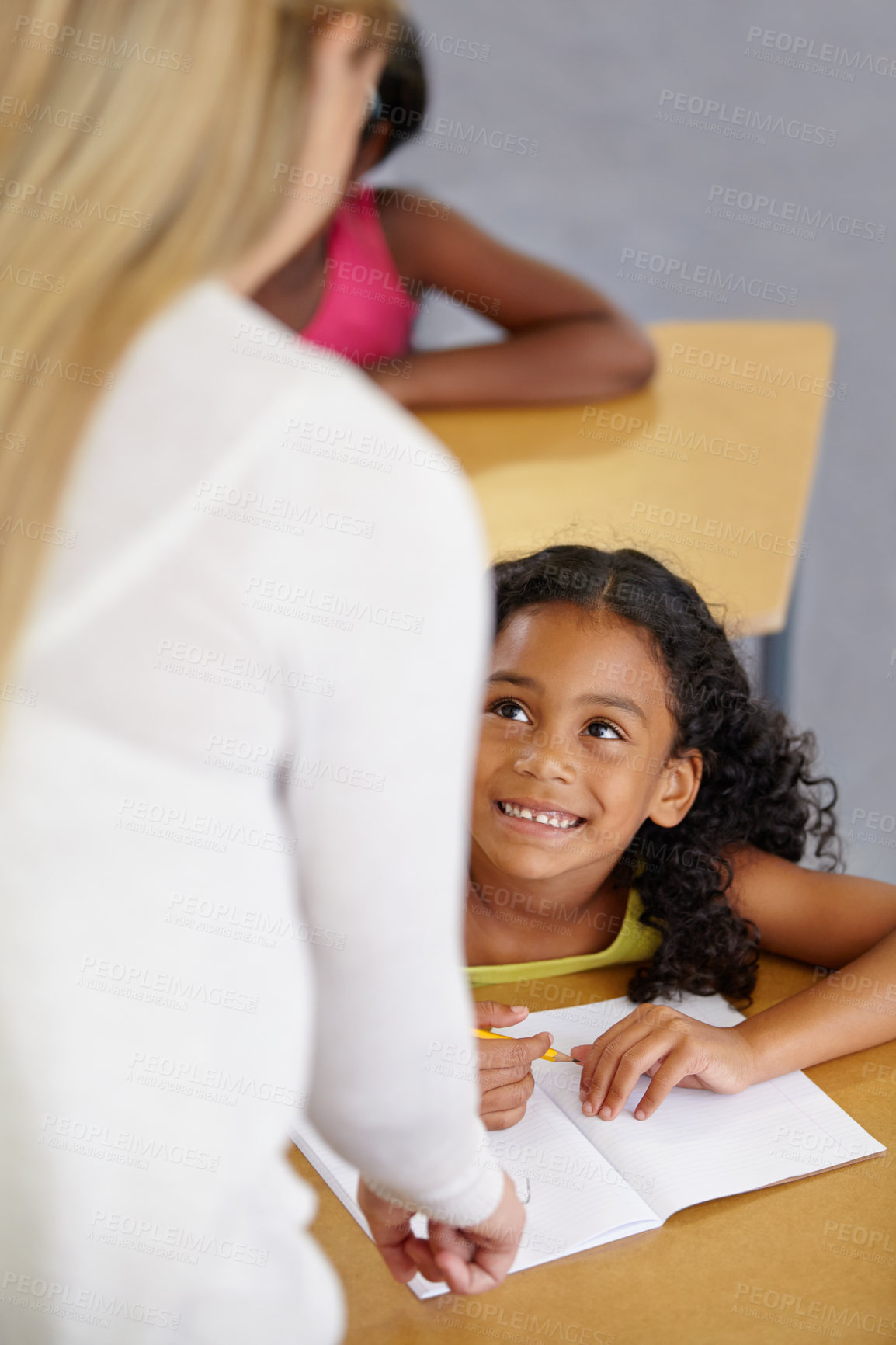 Buy stock photo Teacher woman, classroom and help girl at desk with notebook, advice and knowledge for education. People, learning and development with person, child and check book for progress, school or academy