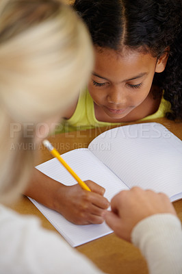 Buy stock photo Teacher help student, education and writing in notebook with pencil, teaching and learning for growth and development. People in classroom to learn, academic study with young girl and woman at school
