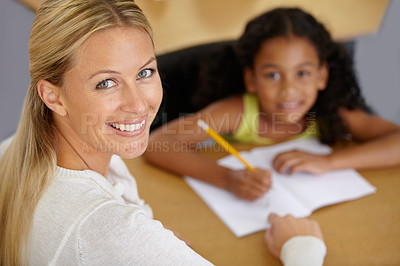 Buy stock photo Portrait of a pretty teacher helping her student with homework