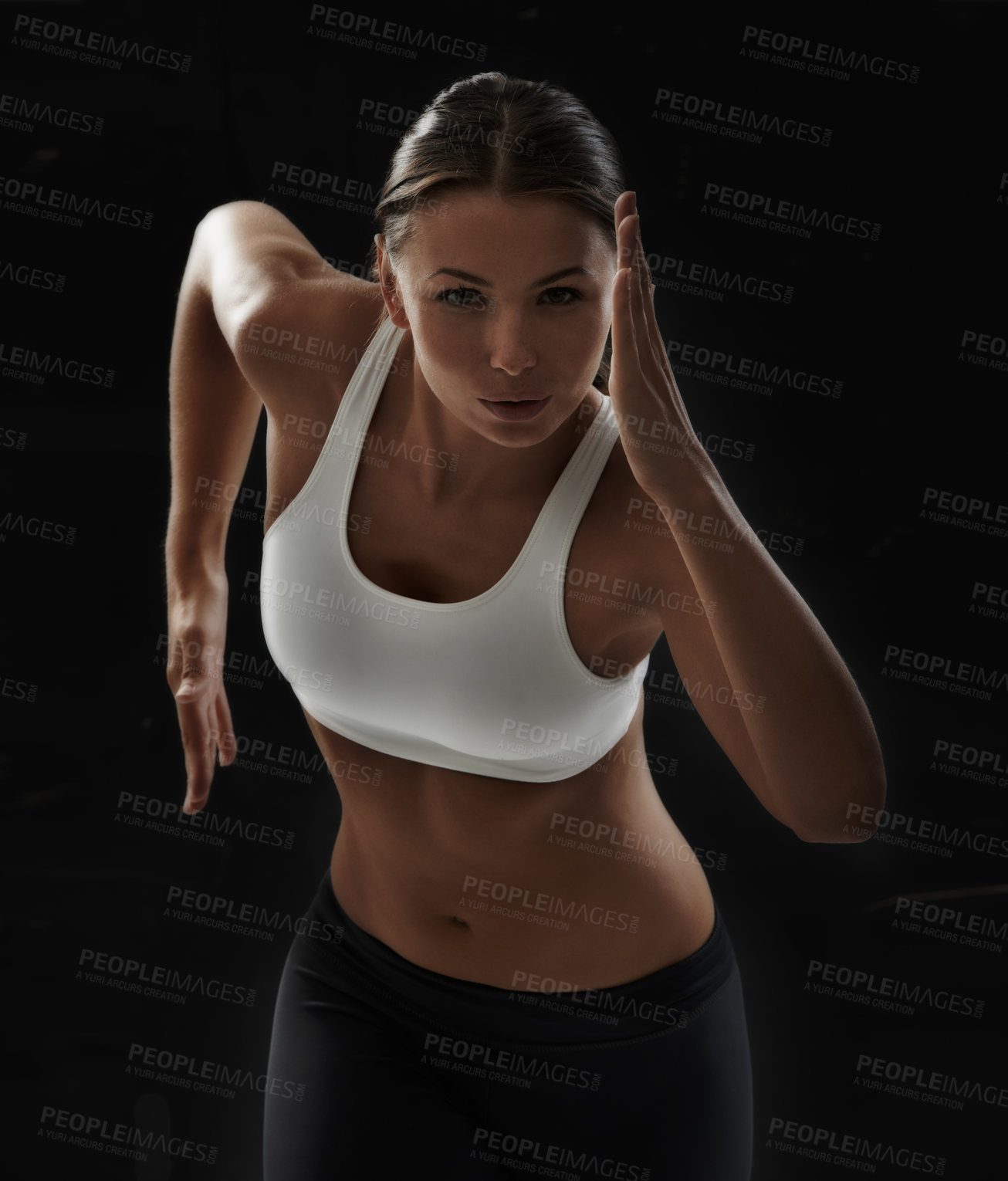 Buy stock photo A pretty young woman sprinting on a black background