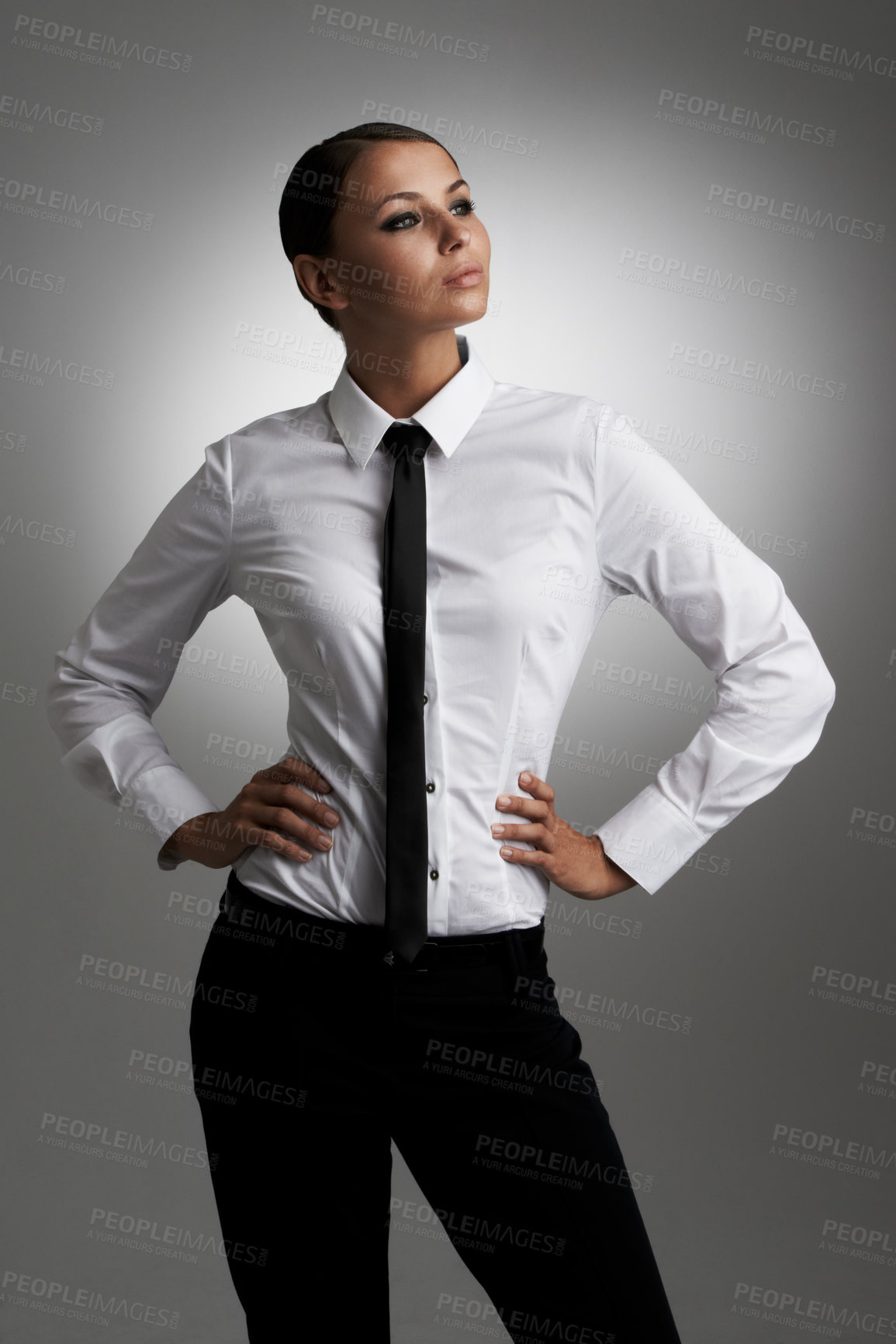 Buy stock photo A young woman wearing shirt and tie looking sideways with her hands on her hips