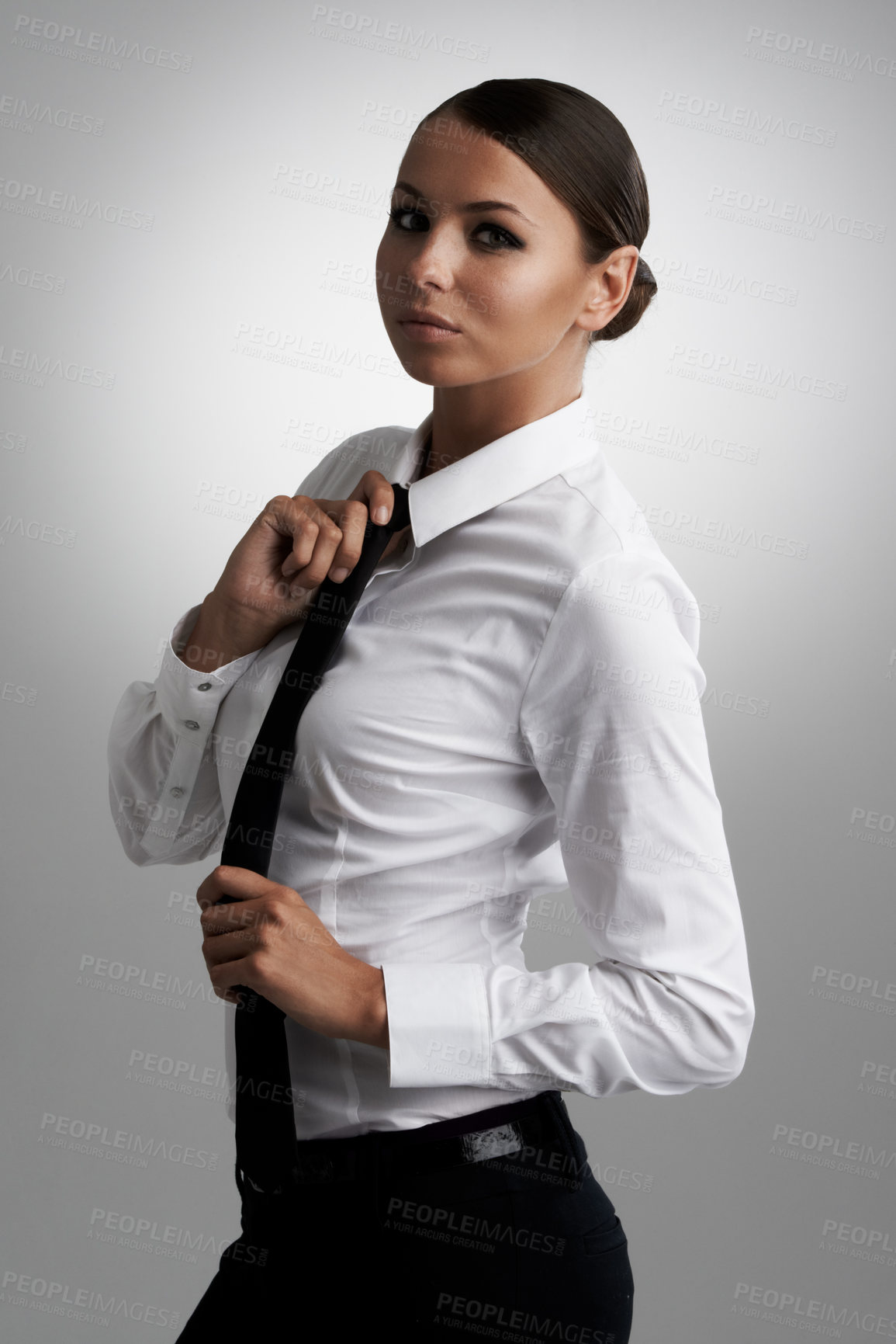 Buy stock photo A beautiful young woman straightening her tie while looking at the camera