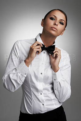 Buy stock photo An attractive young woman straightening her bowtie - portrait