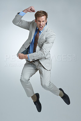 Buy stock photo Businessman, celebration and jumping for achievement in portrait, studio and fist pump for triumph. Male person, professional and victory or success, cheering and energy or win by gray background