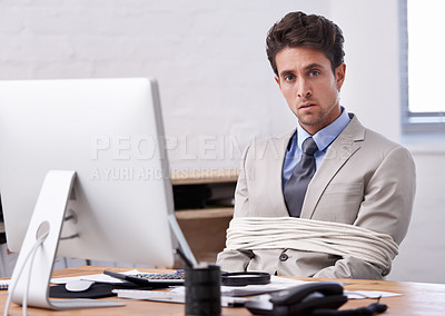 Buy stock photo A handsome young businessman tied up and sitting at his desk