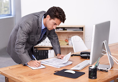 Buy stock photo A handsome businessman multitasking at his desk