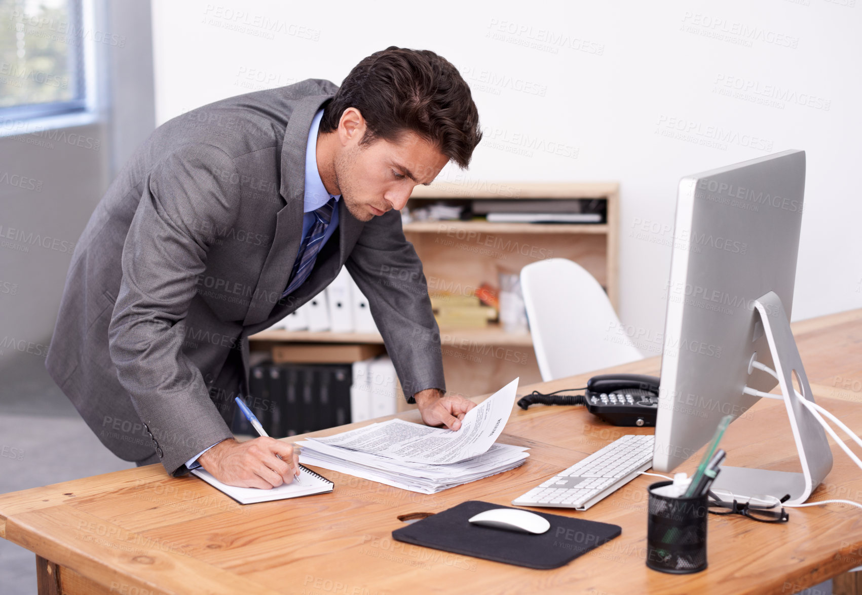 Buy stock photo A handsome businessman multitasking at his desk