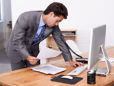 Buy stock photo Businessman, phone call and multitasking on computer in office, networking and technology in workplace. Young accountant, talking or landline with paperwork, consultation or finance advice in company