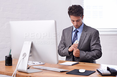 Buy stock photo A young businessman putting cash in his pocket