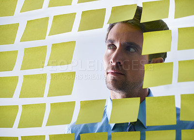 Buy stock photo Businessman, face and thinking in planning, sticky note or brainstorming tasks on glass board at office. Thoughtful man contemplating business decision, strategy or schedule in wonder at workplace