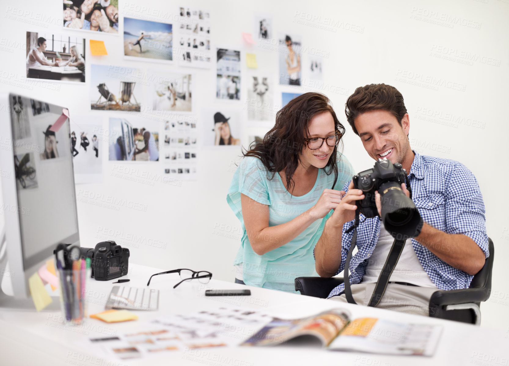 Buy stock photo A photographer looking at his images in his office with his assistant
