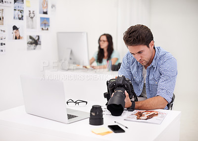 Buy stock photo Camera, office and photographer looking at photoshoot in a studio or workshop for production. Creative, photography and young artist with dslr equipment for picture inspection in modern workplace.