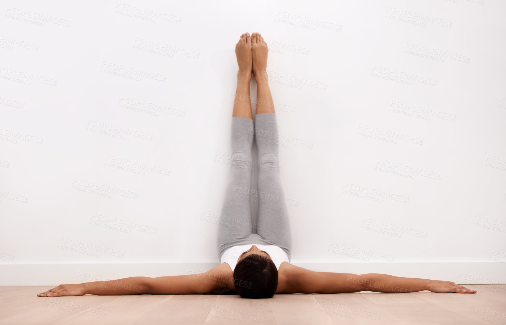 Buy stock photo A young woman stretching against a wall before exercise