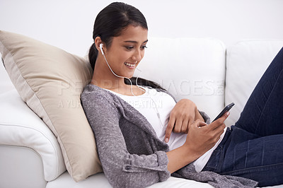 Buy stock photo Young woman, smartphone and earphones, relax on couch with social media, communication and music. Listening to radio, podcast or watch video online, website or blog with mobile app and tech at home