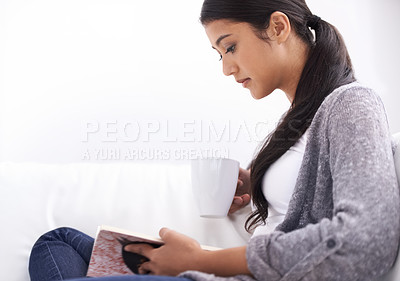 Buy stock photo Woman, reading book and coffee for home education, learning or literature, language or knowledge on sofa. Young student or person relax with tea in living room and novel, fiction or story for leisure