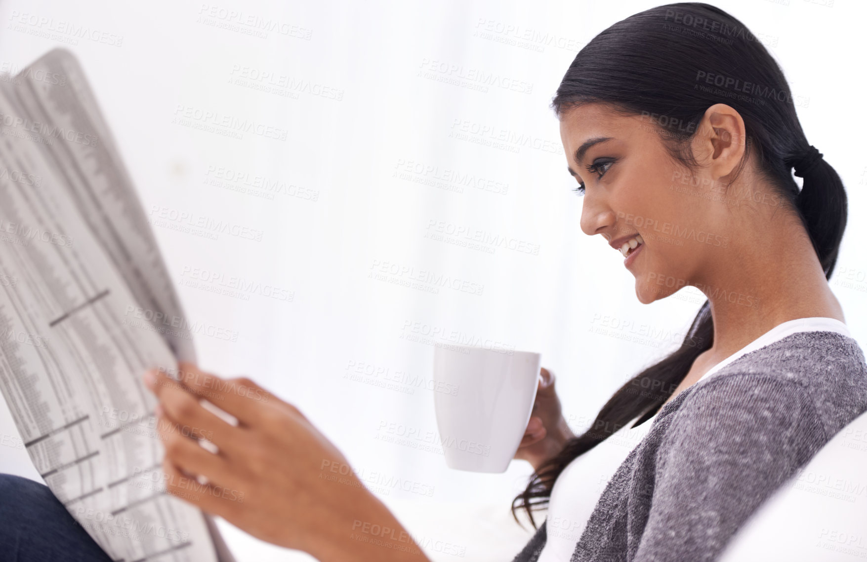 Buy stock photo Happy woman, reading and newspaper in a home in the morning with story, coffee and news. Relax, press print and calm female person from India with paper publication and tea in house with a smile