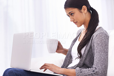 Buy stock photo A gorgeous young woman browsing the internet while enjoying a cup of coffee