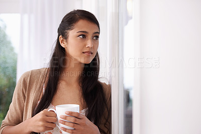 Buy stock photo Coffee, thinking and Indian woman by window in home for relaxing, comfortable and calm in living room. Apartment, morning and person with thoughtful, wonder and drinking hot beverage, tea or caffeine