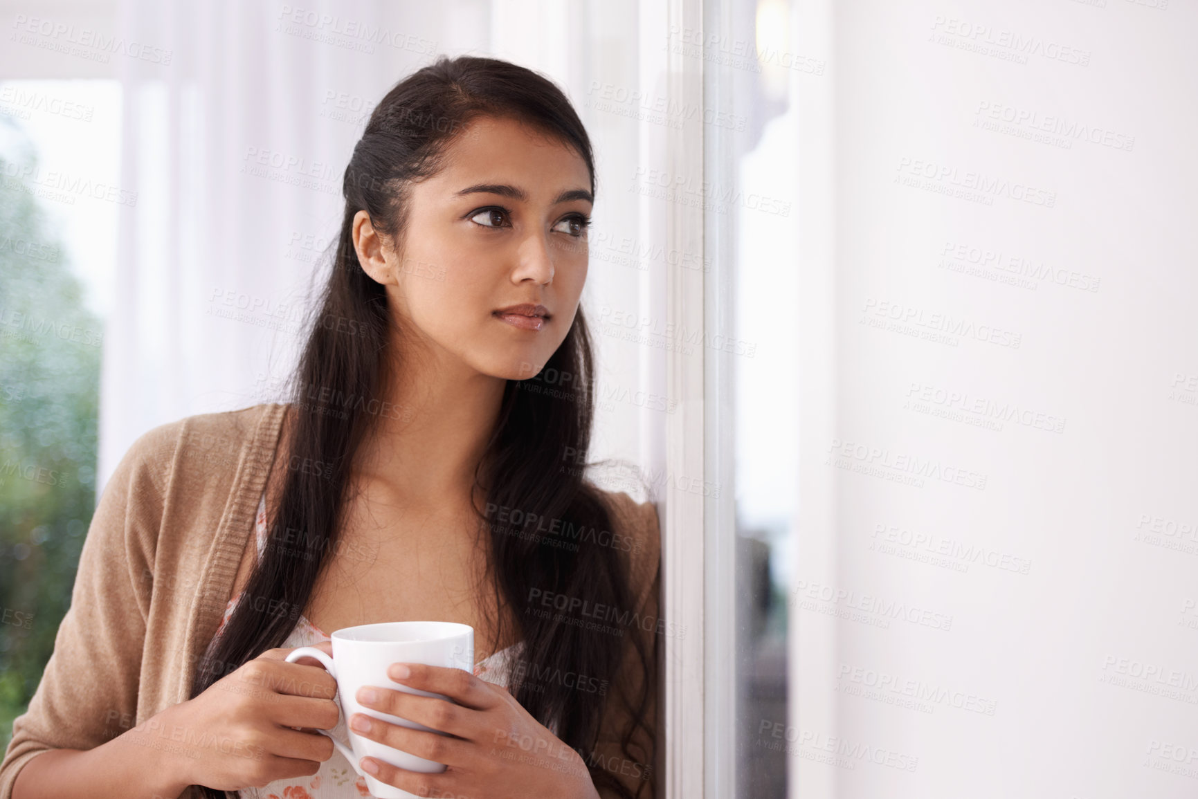 Buy stock photo Coffee, thinking and Indian woman by window in home for relaxing, comfortable and calm in living room. Apartment, morning and person with thoughtful, wonder and drinking hot beverage, tea or caffeine