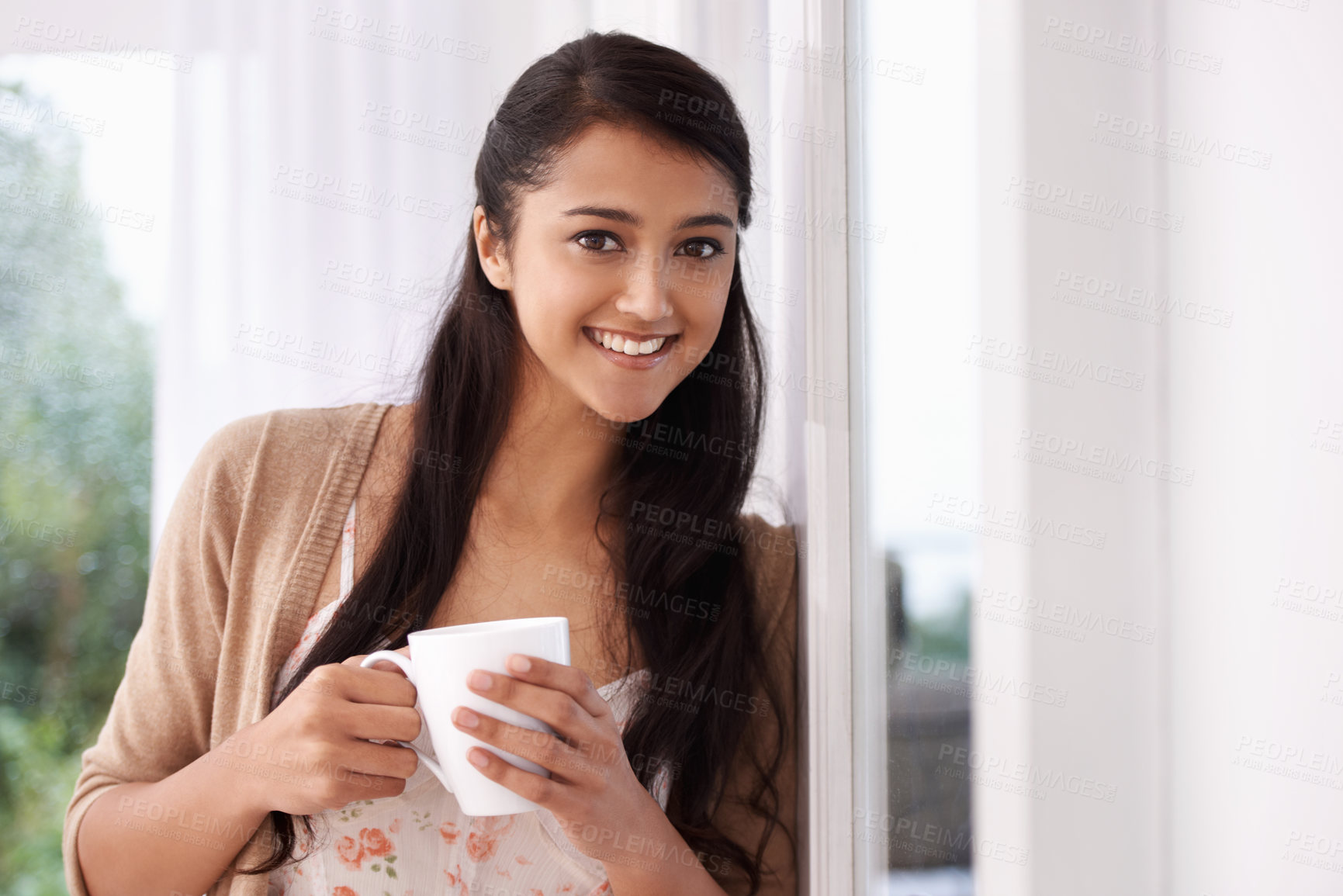 Buy stock photo Coffee, happy and portrait of Indian woman by window for relaxing, comfortable and calm in home. Apartment, morning and person smile with mug drinking hot beverage, tea and caffeine in living room