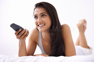 Buy stock photo Happy woman, watching tv and relax on bed for entertainment, news or streaming at home. Face of young female person smile on weekend with remote for morning movie, series or shows lying in bedroom