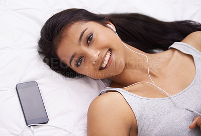 Buy stock photo Woman, relax on bed and phone for music with smile for podcast, audio and streaming at home. Portrait of a young person on a break with mobile app and screen for listening to happy song in bedroom