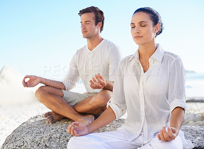 Buy stock photo A young couple performing a relaxing yoga routine together on the beach