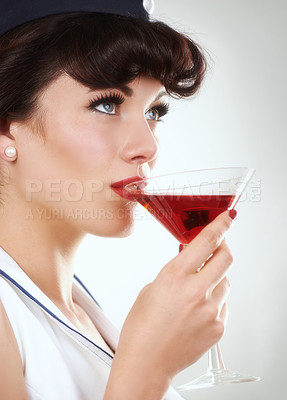 Buy stock photo Glass, flight attendant and woman drink alcohol in studio isolated on a white background. Martini, red cocktail and an air hostess enjoy beverage, vintage pin up girl or stewardess travel on journey
