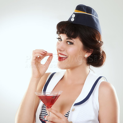 Buy stock photo Portrait, stewardess and happy woman with alcohol to drink in studio isolated on white background. Face, martini cocktail glass and air hostess eating cherry, travel or vintage pin up girl on journey