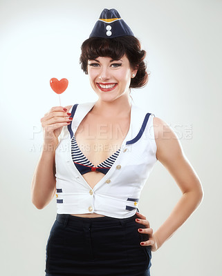Buy stock photo Portrait, smile of woman and sailor with lollipop in studio isolated on a white background. Face, candy and happy air hostess with sugar food, heart sweets and travel dessert for vintage pin up girl