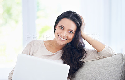 Buy stock photo A pretty woman sitting on her couch with her laptop