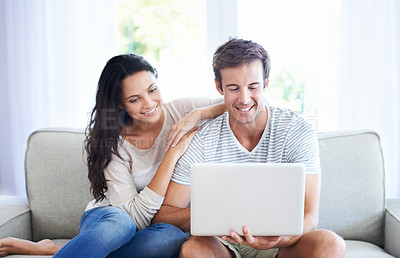Buy stock photo A young couple relaxing on the couch using a laptop