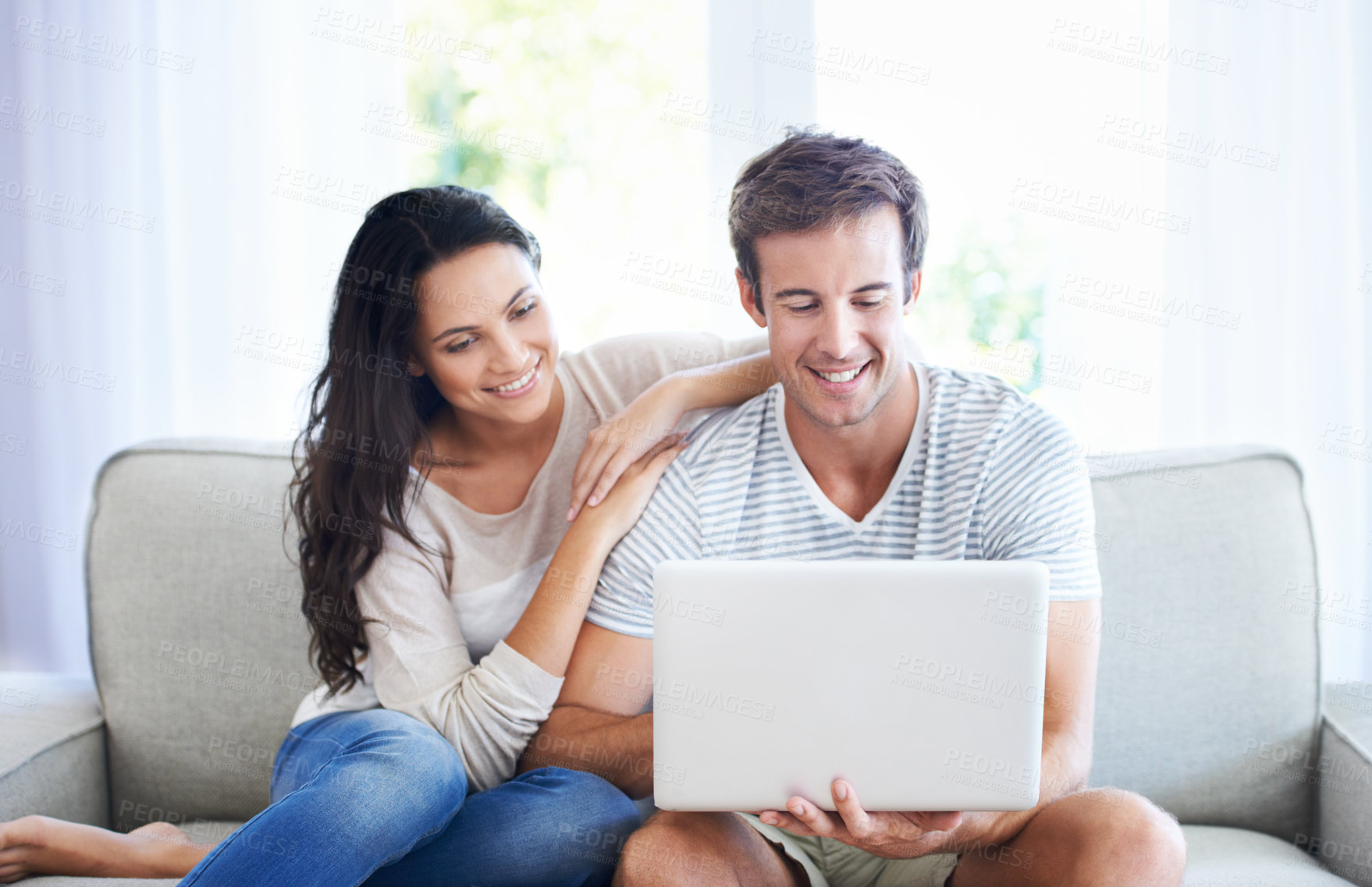 Buy stock photo A young couple relaxing on the couch using a laptop