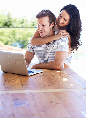 Buy stock photo A young couple using their laptop on the patio