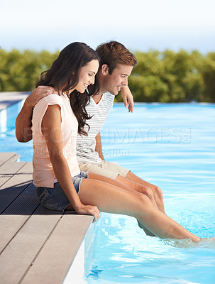 Buy stock photo A young couple sitting by a pool