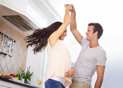 Buy stock photo A young couple playfully dancing in the kitchen