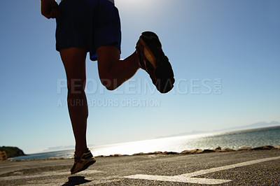 Buy stock photo Person, running and asphalt at beach for fitness, workout or outdoor cardio training on a sunny day. Closeup of athlete legs on run, sprint or race on road or street by the ocean coast on mockup