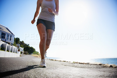 Buy stock photo Woman, running and asphalt at beach for fitness, workout or outdoor cardio training on a sunny day. Closeup of athlete legs on run, sprint or race on road or street by the ocean coast on mockup space