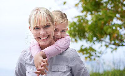 Buy stock photo A beautiful young mother smiling as she gives her daughter a piggyback ride outside