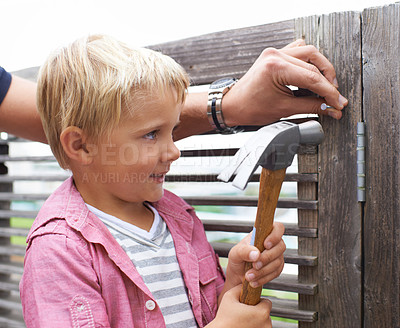 Buy stock photo Smile, hammer and young child doing maintenance on wood gate for fun or learning. Happy, equipment and cute boy kid working on repairs with tool for home improvement outdoor at modern house.