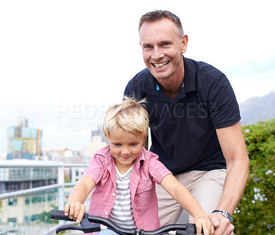 Buy stock photo A handsome father teaching his young son how to ride a bike