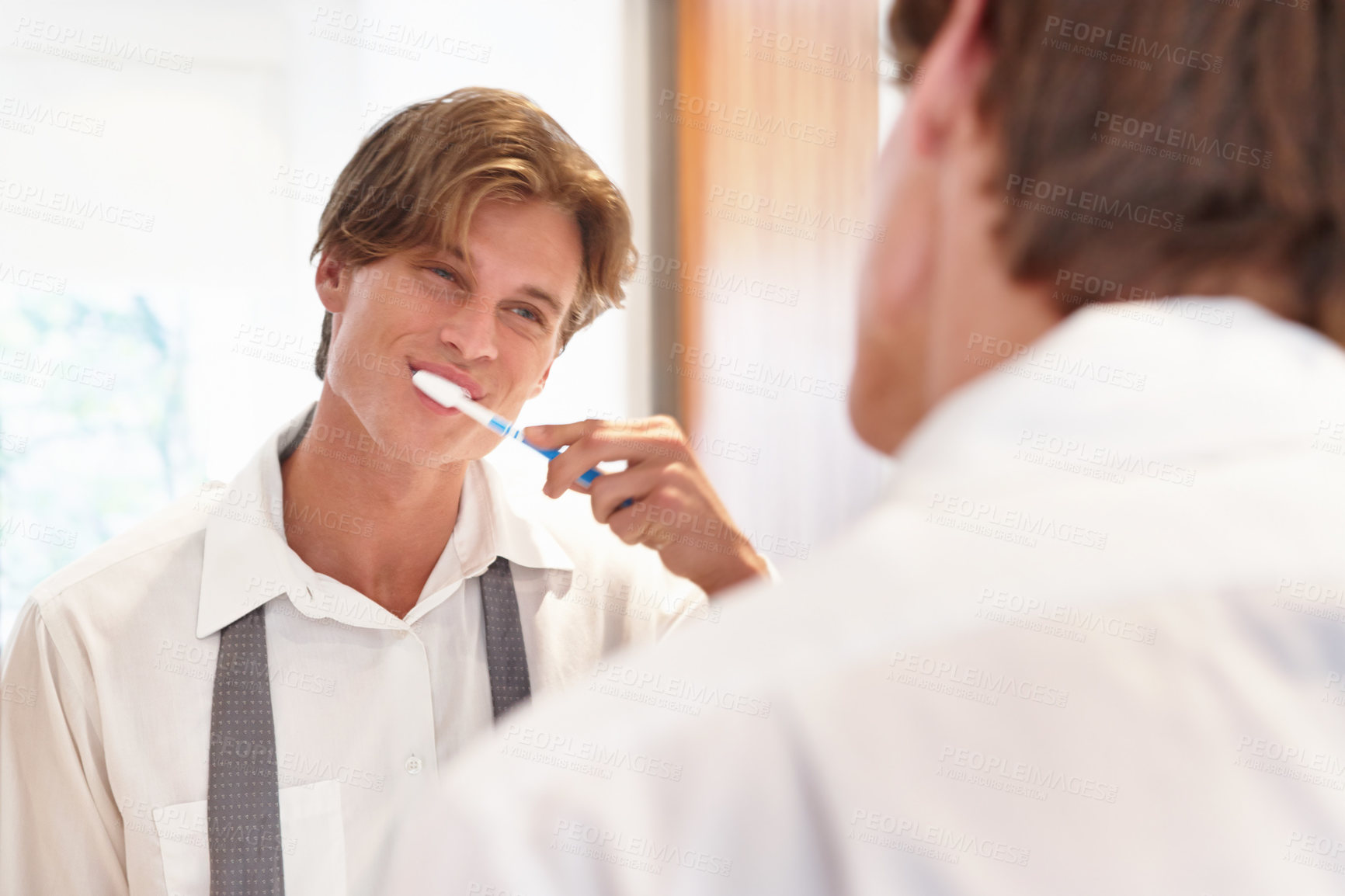 Buy stock photo A young man brushing his teeth in the morning