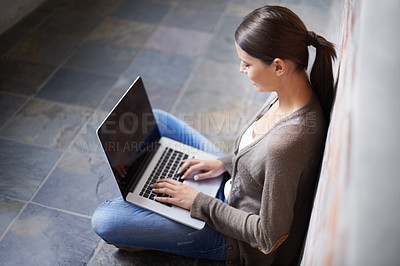 Buy stock photo Shot of an attractive young woman working on her laptop while sitting on the floor