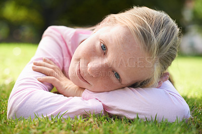Buy stock photo Portrait, curious and girl child lying in grass for fun, play and adventure in nature. Face, relax and kid resting, easy and chilling in a garden for games, exploration and learning on the weekend
