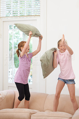 Buy stock photo Children, siblings and pillow fight on a sofa with fun, games and playing in their home together. Family, girl and kids in a living room with freedom, energy and bonding in entertainment in a house