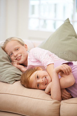 Buy stock photo Portrait, hug and girl siblings on a sofa with love, comfort and care, resting and bonding in their home together. Family, kids and face of sisters lying in a living room with trust and affection